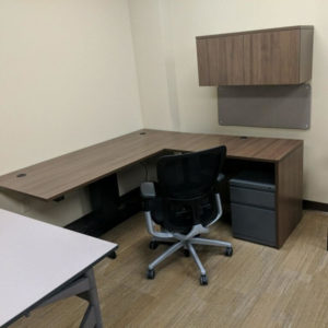 desk shaped in L with return with sit to stand base and overhead