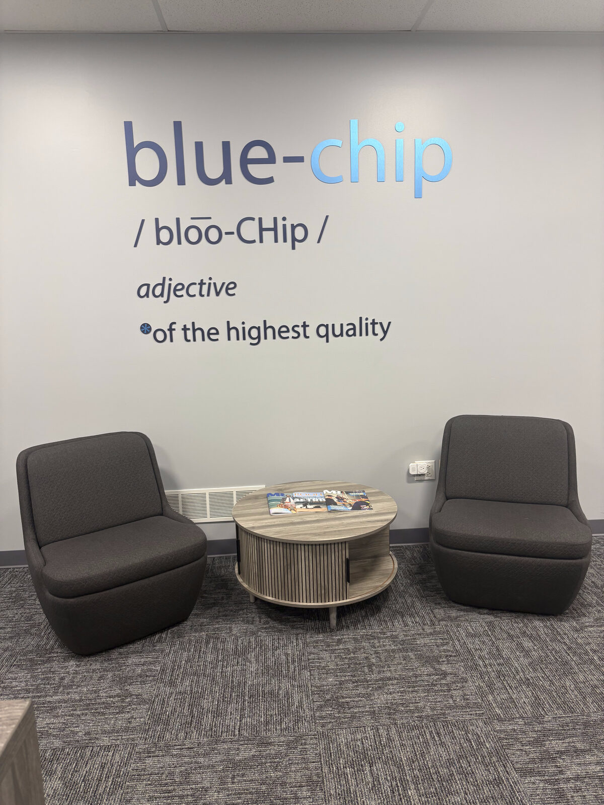 Blue chip definition mural with lounge chairs and coffee table in office seating area