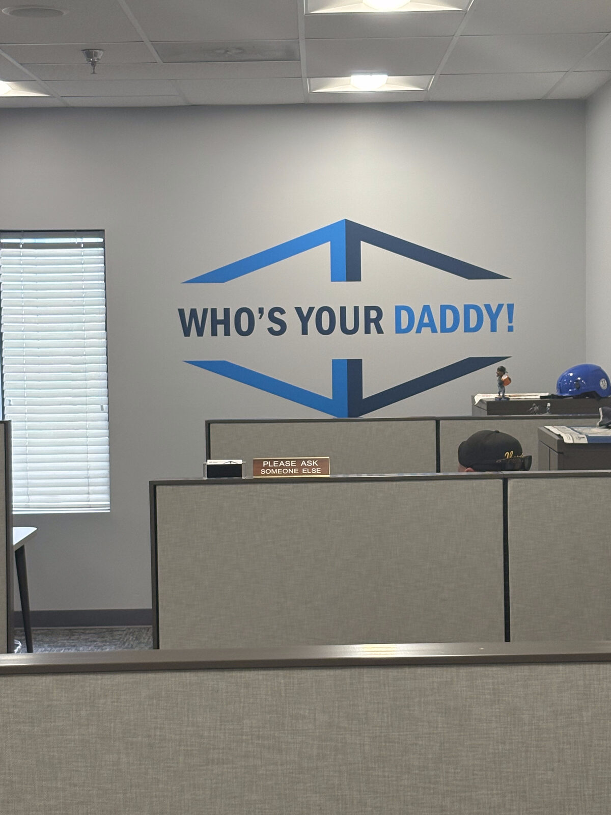 Sales team mural reading Who Is Your Daddy behind office cubicles